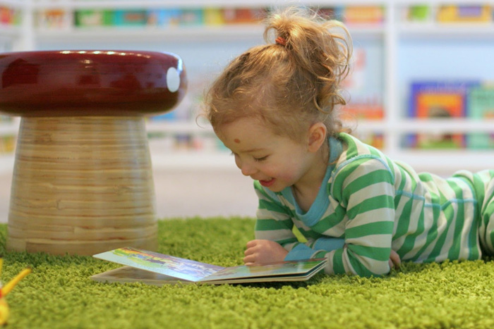 kid reading on fake grass rug (photo)